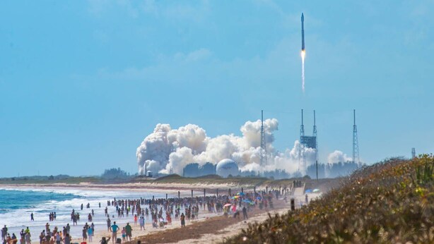 A rocket launch with spectators on a beach.