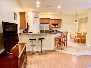 Enjoy cooking in the well-equipped kitchen with a central island, stove, and stainless steel refrigerator.