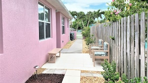 A pink house with a wooden fence, a pathway, and outdoor seating.