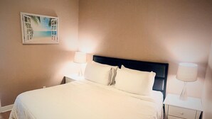 A neatly made bed with white linens, a headboard, and two bedside lamps.