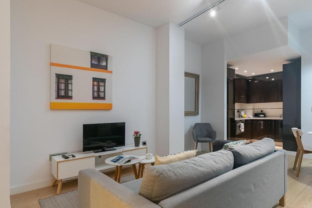 A modern living room with a sofa, TV, and a small table.