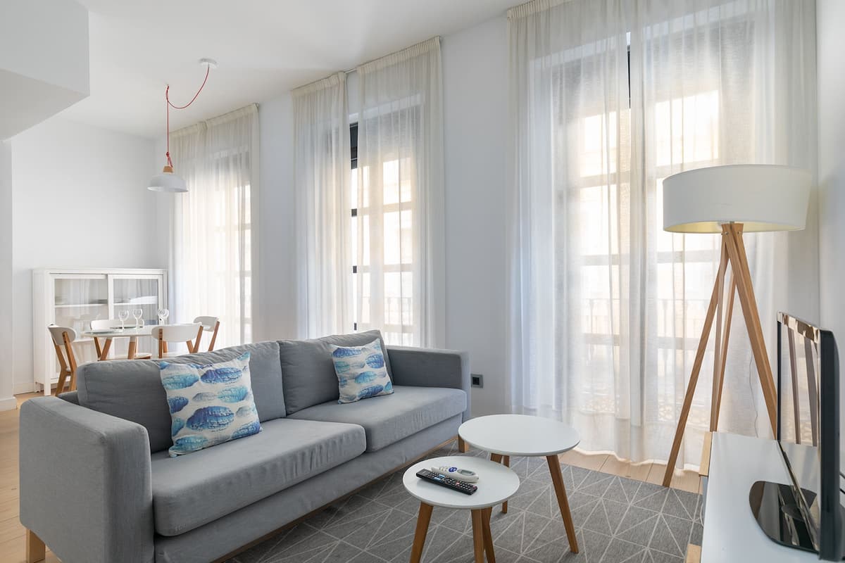 A modern living room with a grey sofa, a small round table, and a floor lamp.