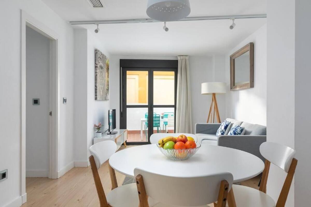 Un espace repas moderne avec une table ronde, des chaises blanches et un saladier rempli de fruits.