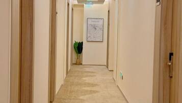 Un pasillo de hotel con pisos alfombrados, puertas de madera y un mapa enmarcado en la pared.