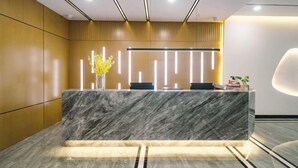 A modern reception area with a marble counter, vertical light strips, and a wooden panel wall. - Zhenjiang July hotel (Zhenjiang)
