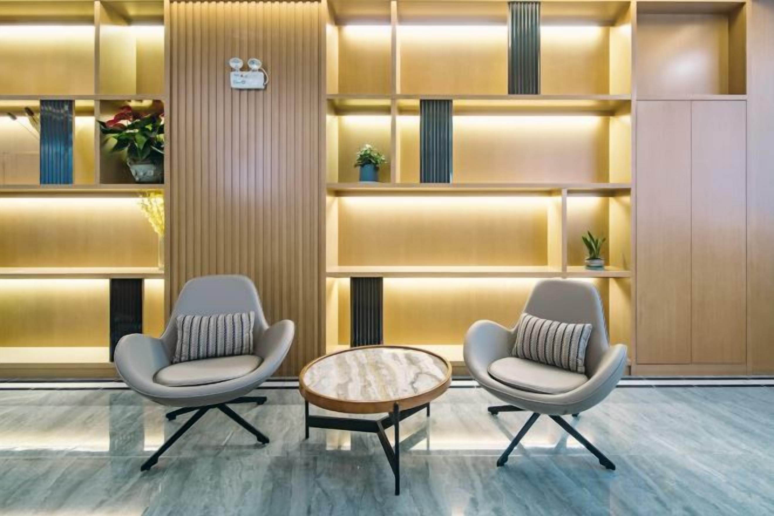 A modern lobby with two armchairs, a round table, and a vertical wooden panel.
