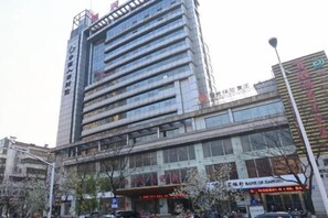 A multi-story building with a modern facade, large windows, and signage indicating a commercial area. - Zhenjiang July hotel (Zhenjiang)