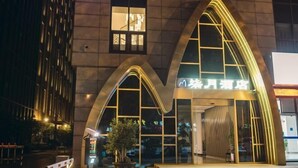 A hotel entrance with a modern design, featuring arched windows and a sign in a foreign language. - Zhenjiang July hotel (Zhenjiang)