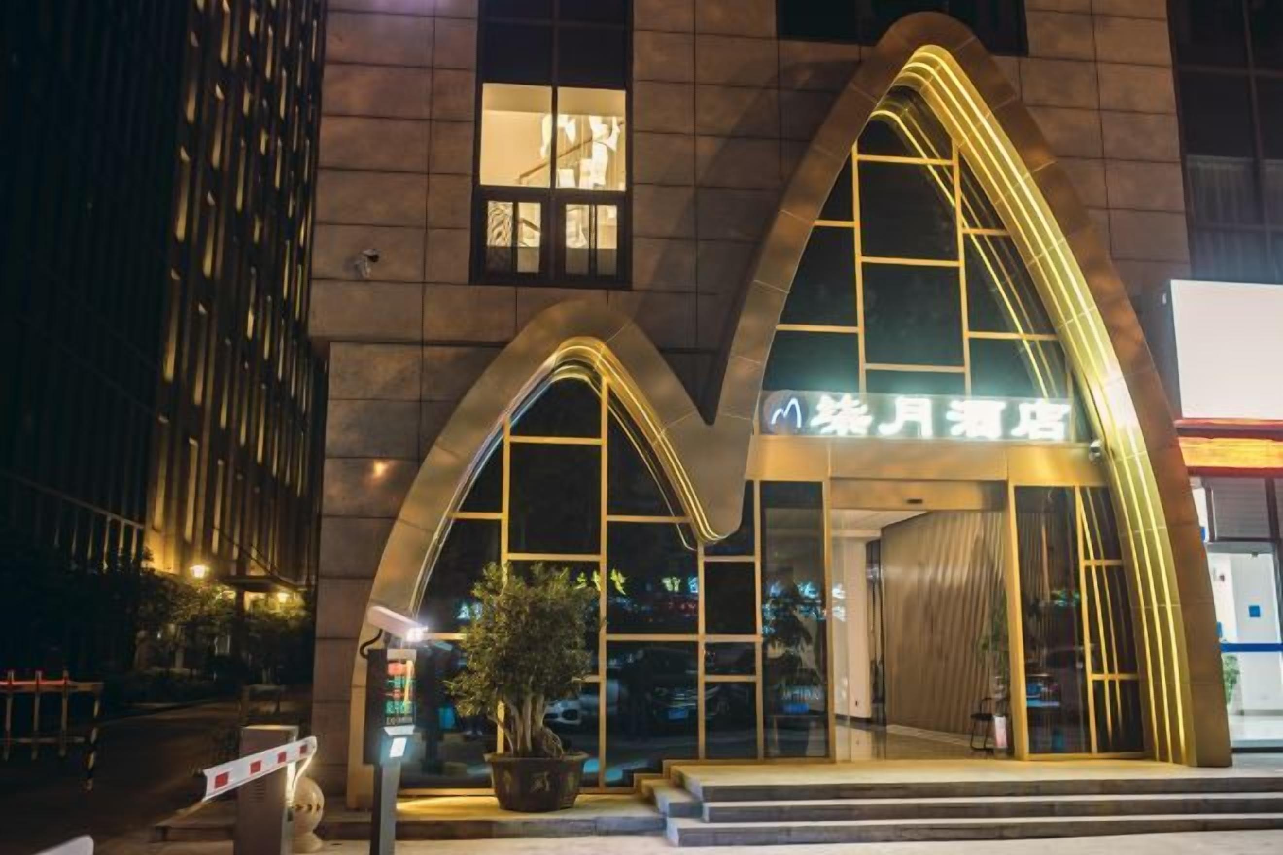A hotel entrance with a distinctive arched facade and illuminated signage.