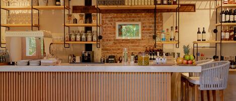 Un área de bar con estantes de madera, luces colgantes y una pared de ladrillo.