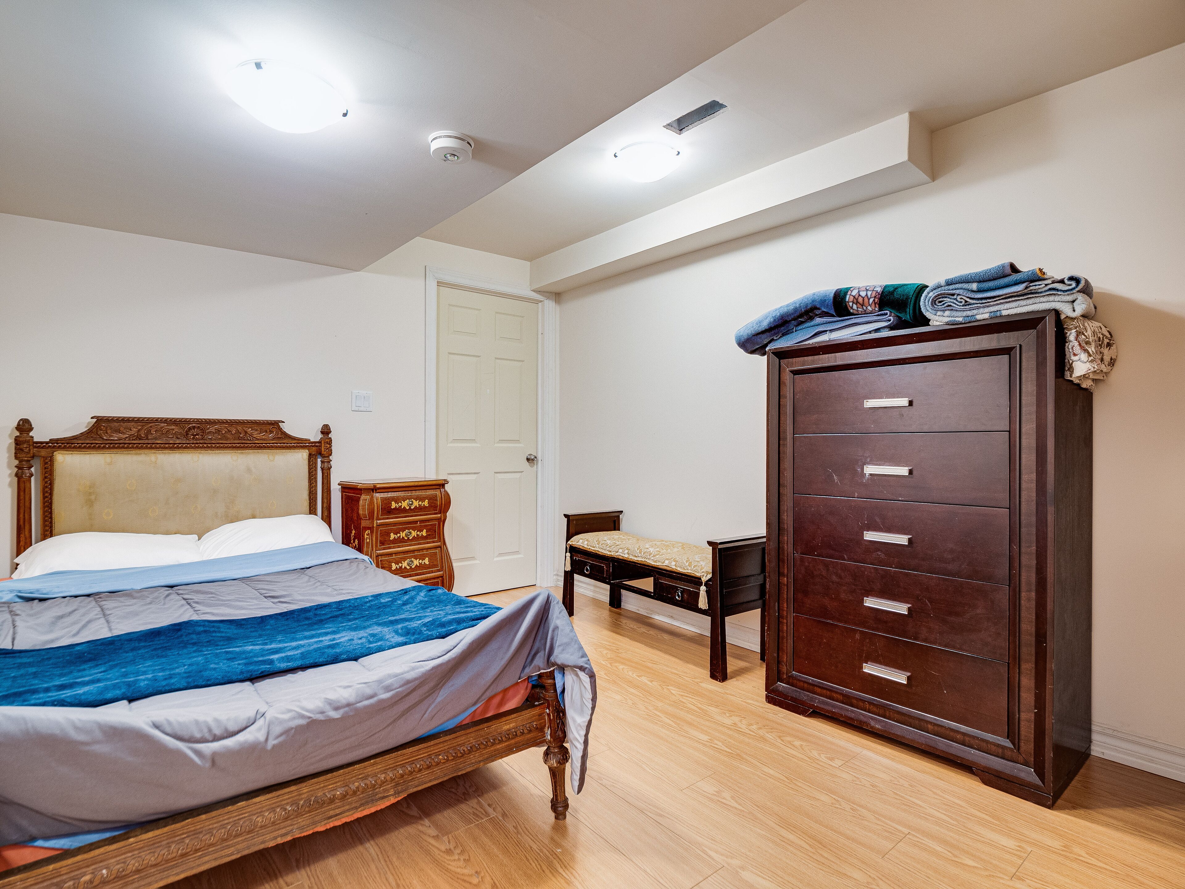 A bedroom with a wooden bed, a dresser, and a door.
