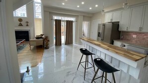 Una cocina amplia con piso de mármol, barra de bar de madera y electrodomésticos modernos.