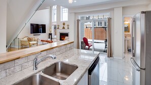 Una cocina moderna con un lavamanos doble, electrodomésticos de acero inoxidable y un comedor con una silla roja.