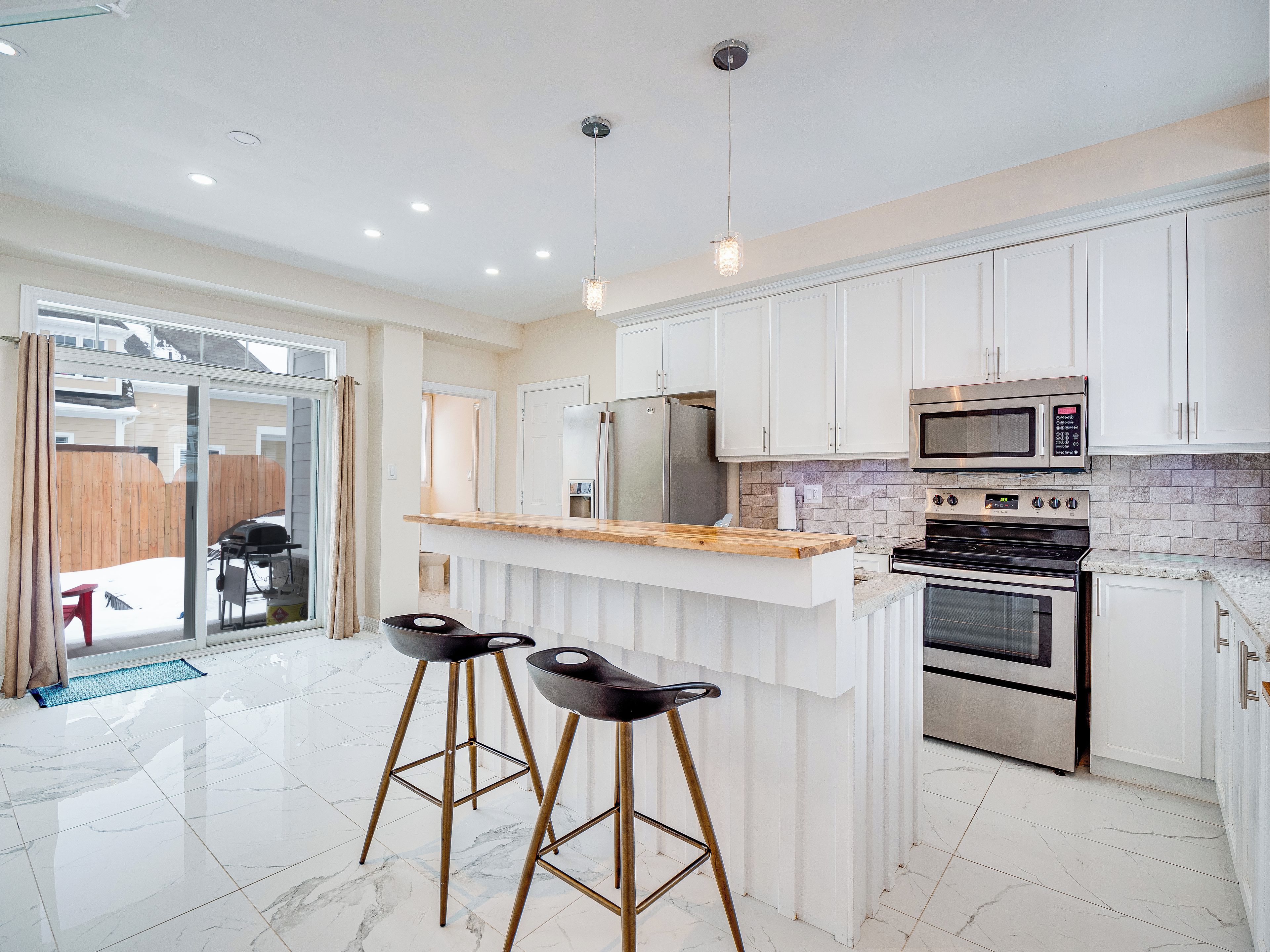 A modern kitchen with white cabinets, a wooden countertop, and stainless steel appliances.