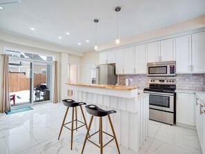 Une cuisine moderne avec des meubles blancs, un plan de travail en bois et des appareils électroménagers en acier inoxydable.