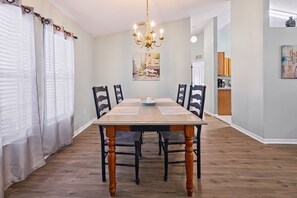A dining area with a wooden table, chairs, a chandelier, and a painting on the wall. - 🌴🍹Tropical Paradise! Heated Pool, Boat Parking, Near Beaches! (Sebastian)