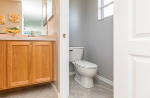 A bathroom with wooden cabinets, a white toilet, and a mirror above the sink. - ☆☀︎❀ Tropical Paradise! Heated Pool, Boat Parking, Near Beaches! (Sebastian)
