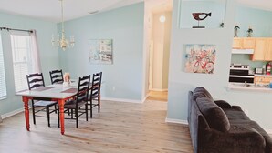 A dining area with a wooden table and chairs, a chandelier, and artwork on the walls.