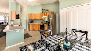A compact kitchen with wooden cabinets, a stainless steel refrigerator, and a checkered table.