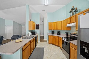 A modern kitchen with wooden cabinets, a stainless steel refrigerator, and a built-in oven. - 🌴🍹Tropical Paradise! Heated Pool, Boat Parking, Near Beaches! (Sebastian)