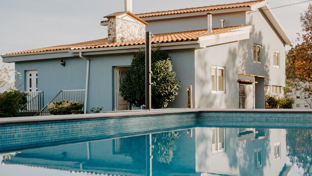 A modern two-story house with a swimming pool in front.