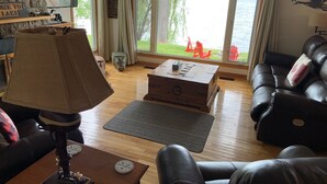 A living room with a fireplace, a large window with a view of a lake, a sofa, and a coffee table.