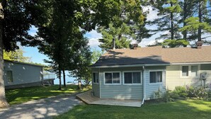 A single-story house with a covered porch, a small deck, and a view of a lake.