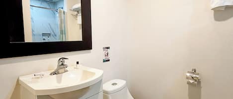 A bathroom with a white sink, a toilet, a mirror, and a towel rack.