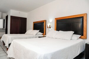 Habitación de hotel con dos camas, un armario de madera, una mesita de noche y una lámpara de pared.