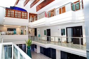 A multi-level hotel lobby with glass railings, a central staircase, and a decorative plant. - Hotel Boutique Plaza Doradas (San José del Cabo)
