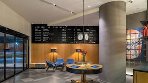 Eine moderne Hotelhalle mit Rezeption, Sitzgelegenheiten und einer Fluganzeige.