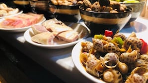 Ein reichhaltiges Buffet mit verschiedenen Speisen, darunter Meeresfrüchte, Fleisch und Gemüse.