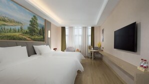 Une chambre d’hôtel avec deux lits, un bureau avec une chaise, un téléviseur à écran plat et un tableau au mur.