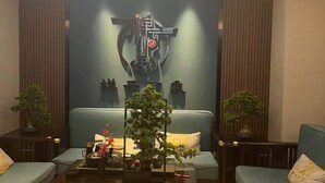 Un salon moderne agrémenté d’une grande œuvre d’art abstraite murale, de deux canapés, d’une table basse et de plantes en pot.