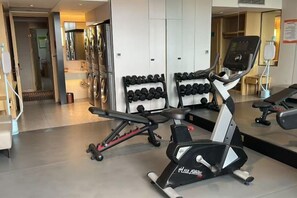 A gym with exercise equipment, including a treadmill and dumbbells. - Vienna International Hotel (Tianjin Meijiang Convention and Exhibition Center) (Tianjin)