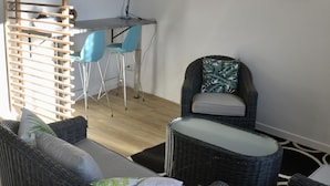 Ett modernt vardagsrum med möbler i rotting, ett skrivbord och en krukväxt.