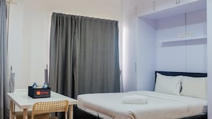 A hotel room with a bed, a desk, a chair, and a wardrobe. - Prime Location Sudirman Park Studio Apartment (Jakarta)