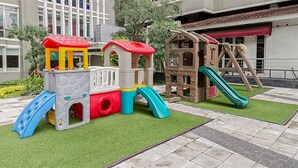 A children's play area with a train set, a slide, and a climbing structure. - Prime Location Sudirman Park Studio Apartment (Jakarta)