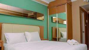 A hotel room with a bed, a nightstand, a mirror, and a wardrobe. - Cozy and Modern Signature Park Grande Studio Apartment (Jakarta)