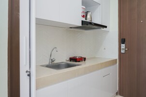 Cozinha com uma pia dupla, um fogão por indução vermelho e armários brancos.
