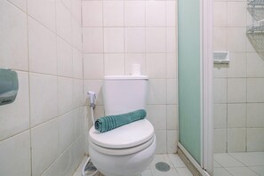 A bathroom with a toilet, a shower, and a hand dryer.
