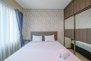 A hotel room with a bed, a wardrobe, and a window with curtains.