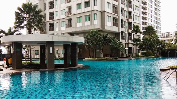 A swimming pool with a circular structure in the center, surrounded by a multi-story building with balconies.