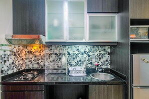 A modern kitchen with dark wood cabinets, a tiled backsplash, a stainless steel sink, and a built-in oven.