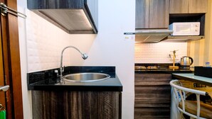 Une cuisine équipée d’un évier en acier inoxydable, de meubles de rangement en bois, d’un four à micro-ondes et d’une bouilloire.