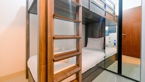 Une pièce avec des lits superposés, une échelle en bois et une porte en verre.