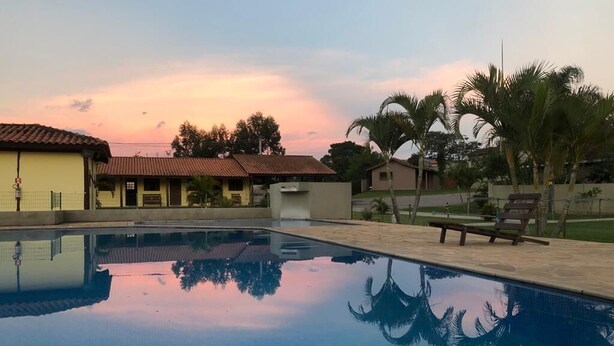 Una piscina con agua cristalina que refleja palmeras y un cielo al atardecer.