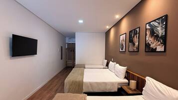 Quarto de hotel com duas camas, televisão de tela plana, obras de arte na parede e um closet espaçoso.
