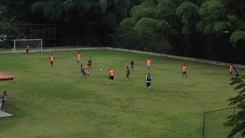A soccer field with players in orange and black jerseys.