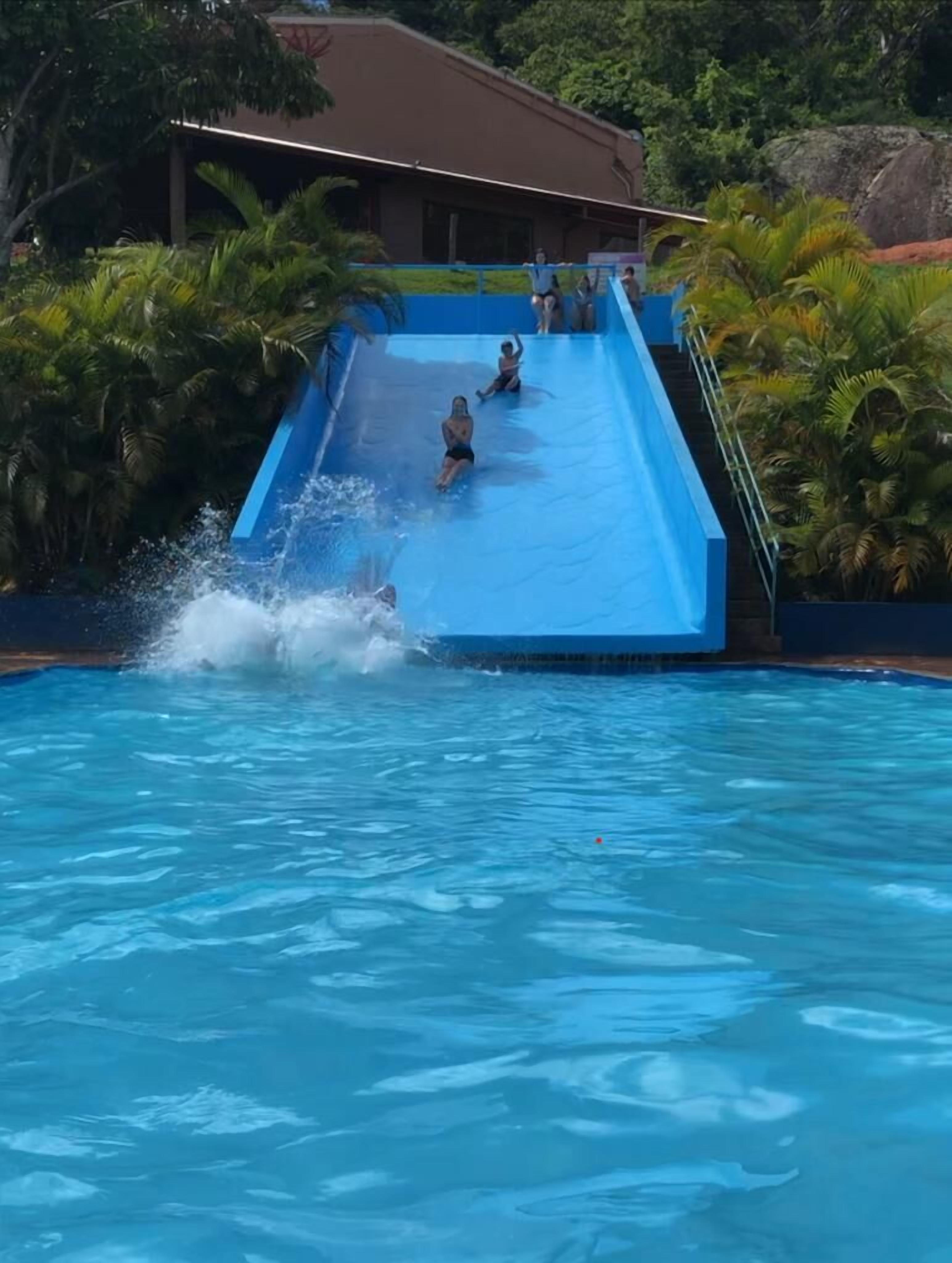 Una piscina con un tobogán azul y un edificio al fondo.